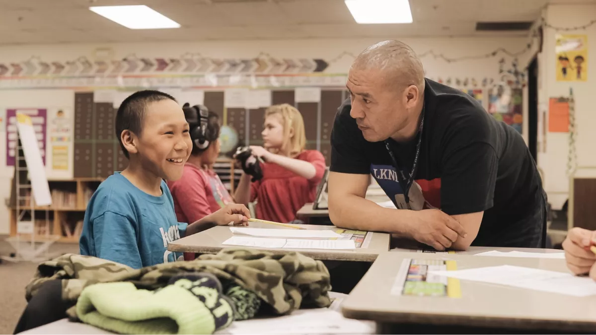 NEA-Alaska Member Charlie Glenn connects one-on-one with a smiling student in the classroom.