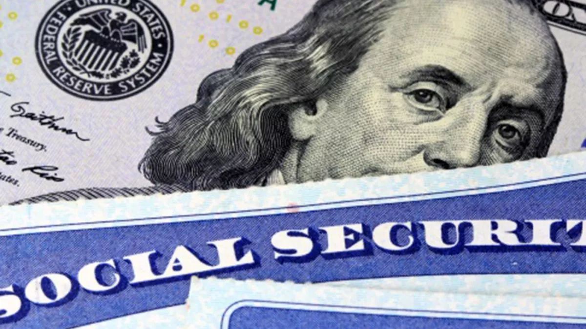 An image of a social security card laid over a hundred dollar bill.