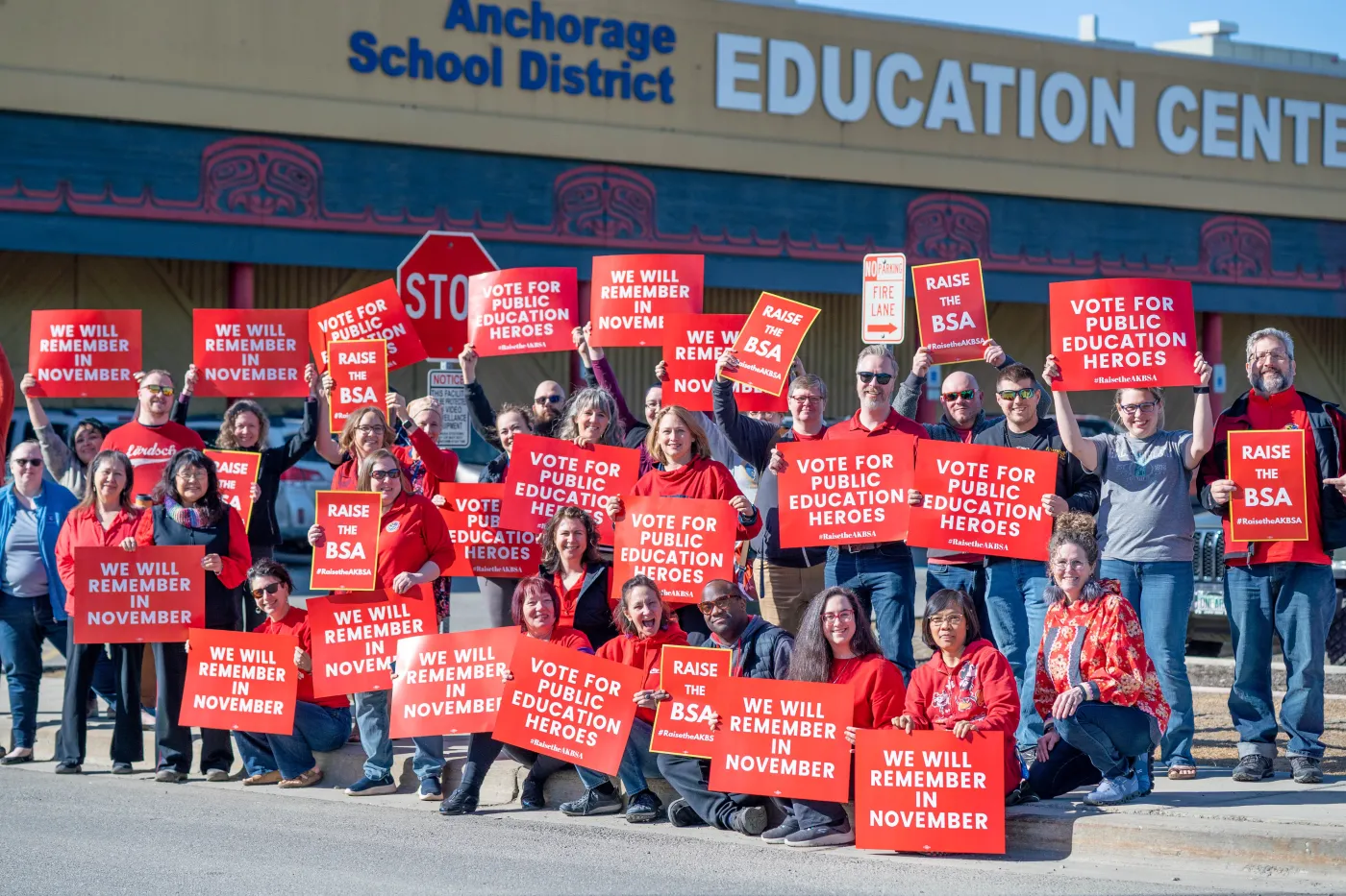 Educators rally with red signs