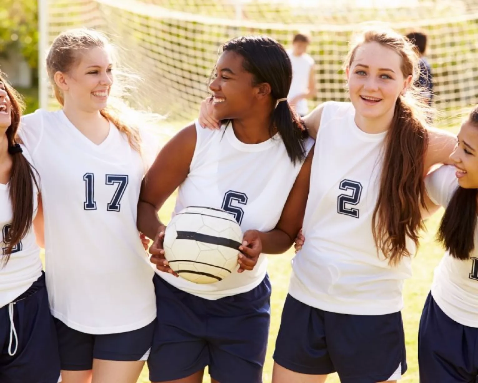 girls pose for a picture together on a soccer field