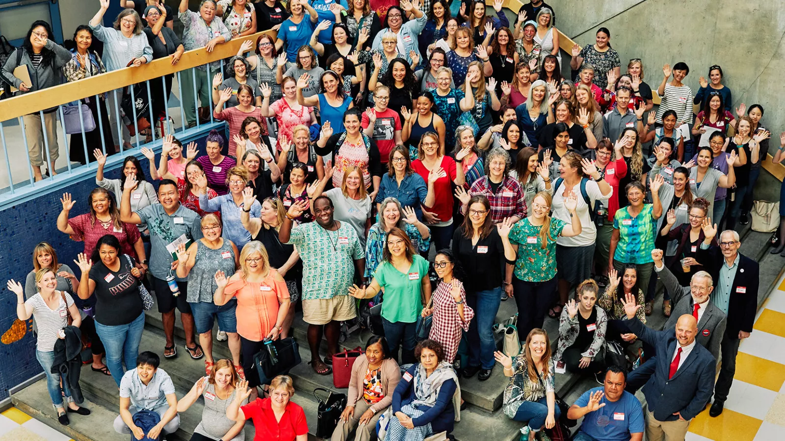 A large group of NEA-Alaska members gathered on steps waving at the camera.