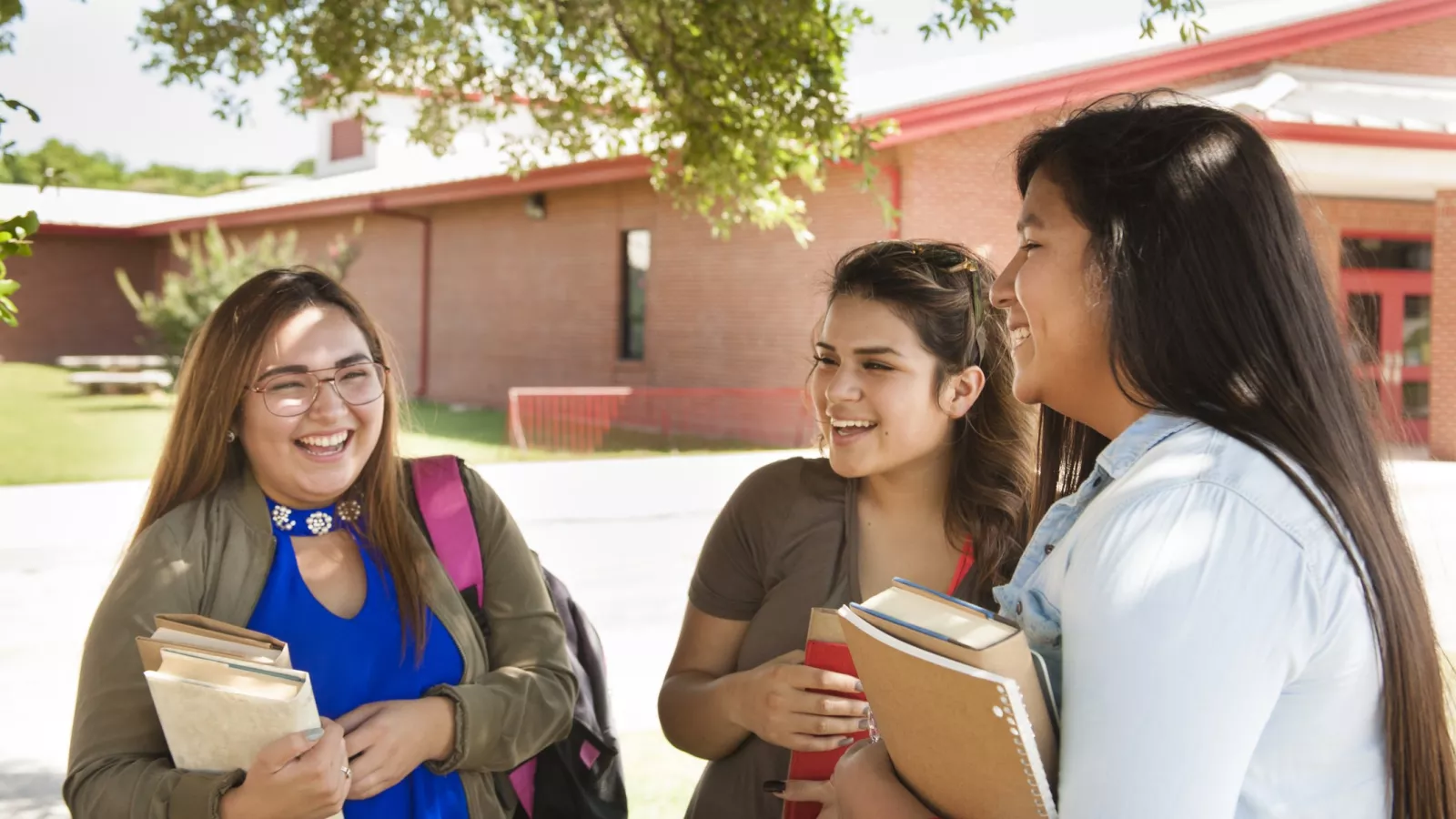 three girls talk outside of their school