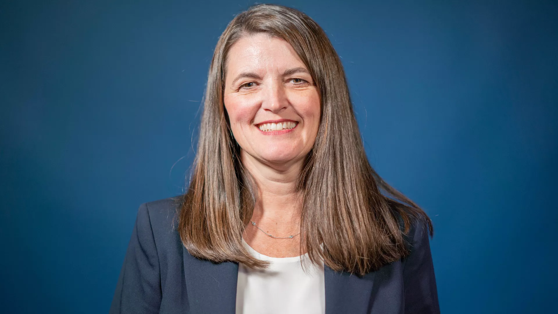 NEA Director Kathy Simpler smiles for a portrait wearing a blue blazer.