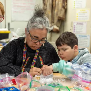 Yvette works on beading with a native student.