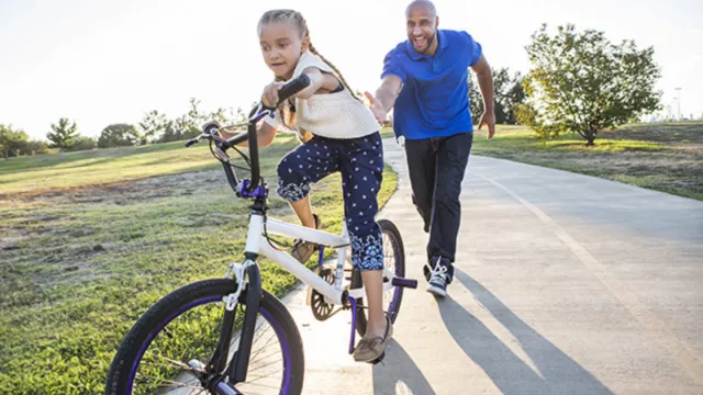 A man helps his daughter learn to ride a bike