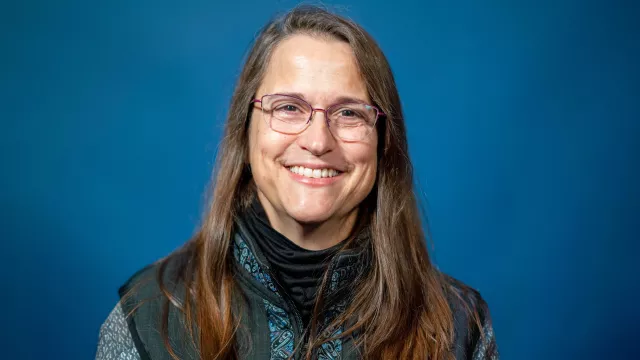 Vice President Laura Capelle smiles for a portrait with a bright blue background.