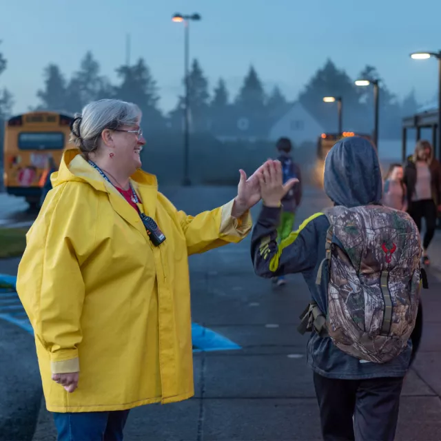 Julia Walker high fives a student while walking to the school bus.