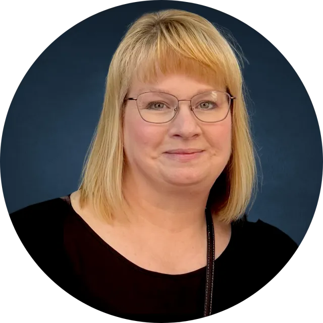 A portrait of a light-skinned woman with blonde hair and glasses