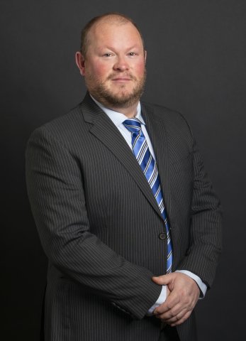 NEA-Alaska Executive Director Zac Mannix poses in a suit and tie for a portrait